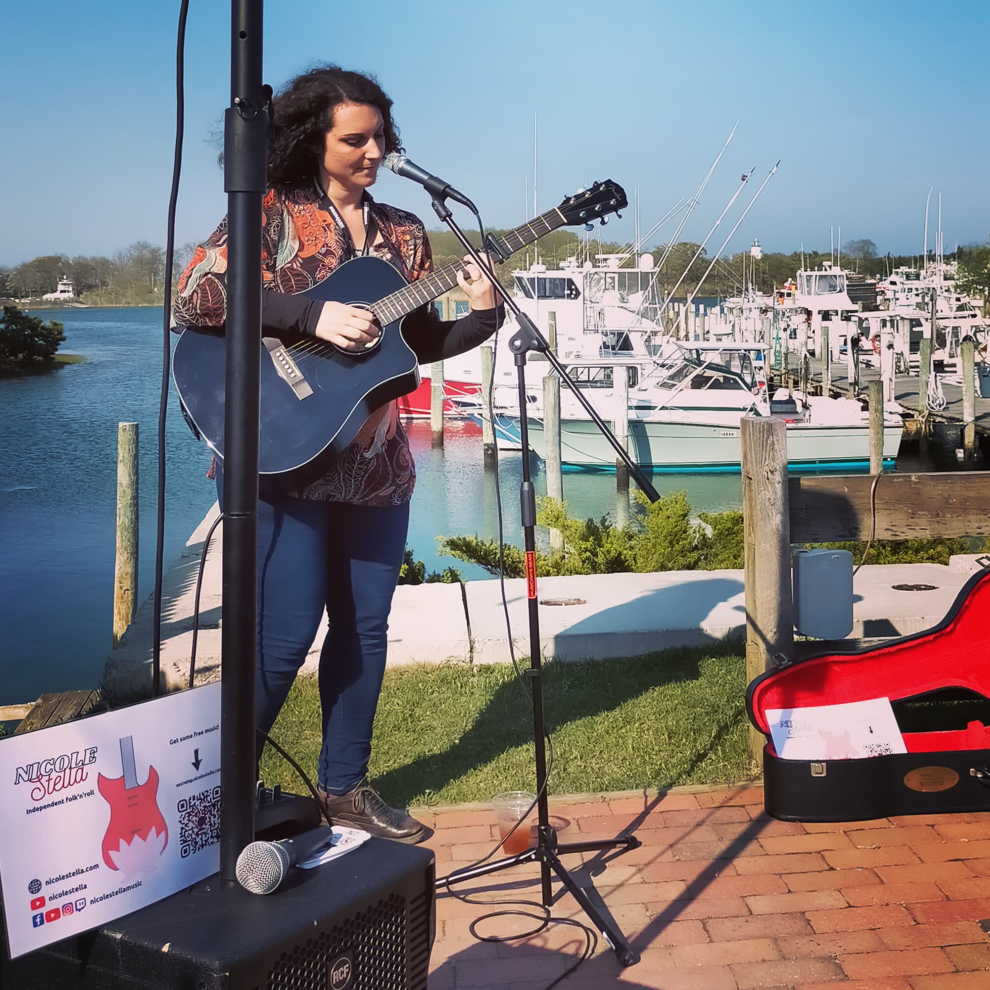 Nicole Stella playing an acoustic guitar at the Montauk Music Festival