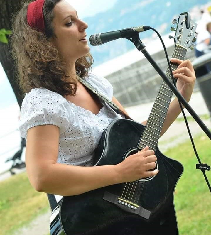 Nicole Stella singing and playing an acoustic guitar at Bellagio in Blues