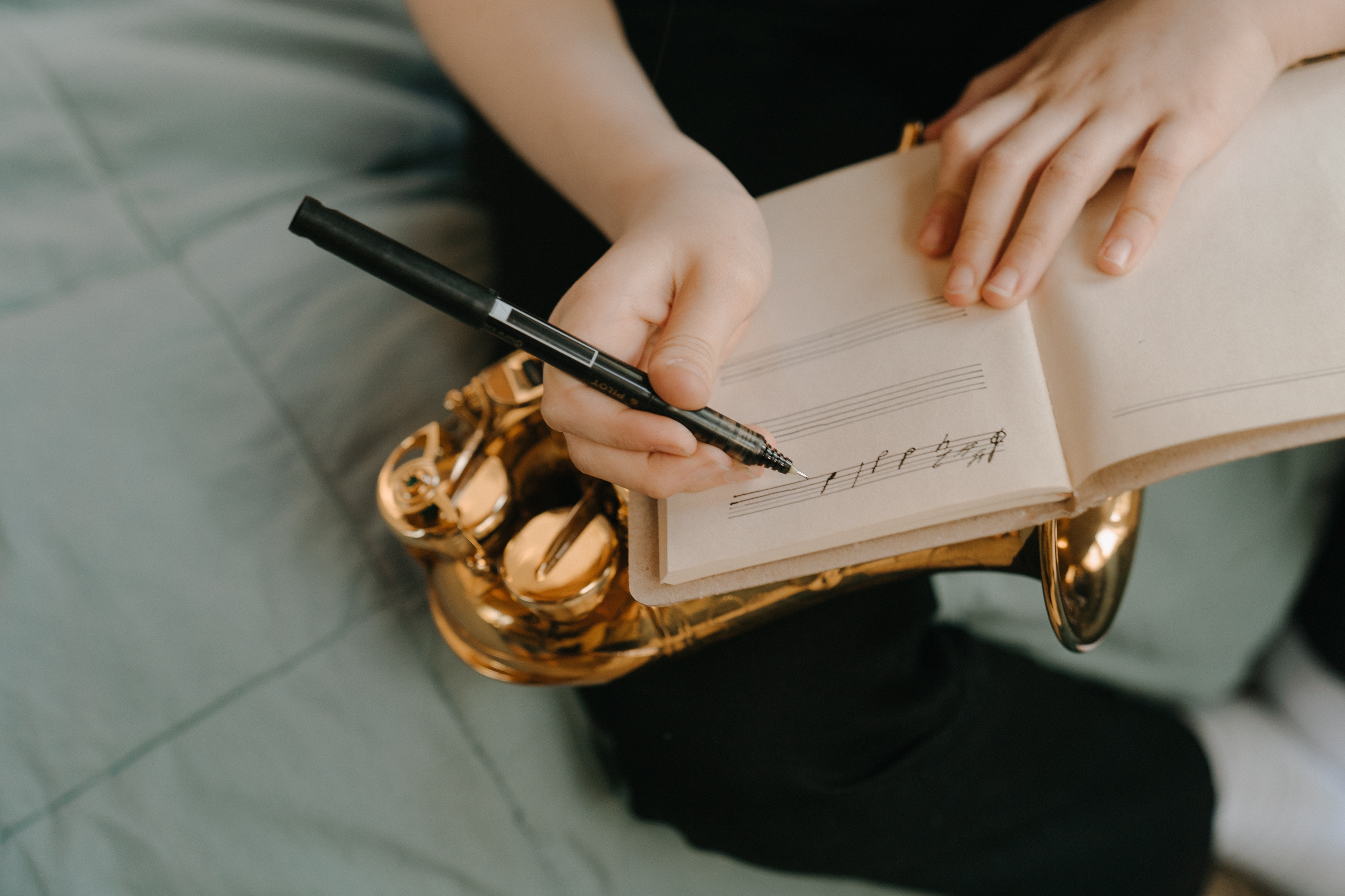 Person writing on a music sheet over a saxophone